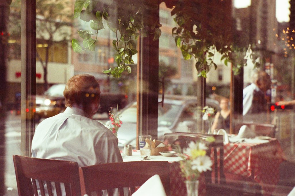 A photo of a person taken through a window sitting in a cafe.